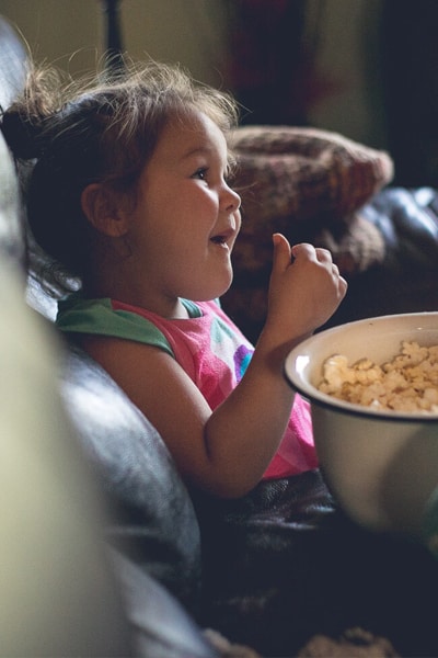 A girl eating popcorn watching a movie