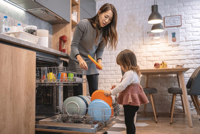 Toddler putting dishes away with mom as part of her age appropriate chores